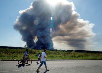 PENDUDUK berjalan melepasi kepulan asap akibat kebakaran di kompleks logistik syarikat e-dagang Russia, Wildberries di bandar Elektrostal di pinggir Moscow.- AFP