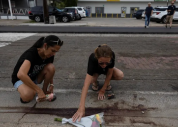 DUA wanita meletakkan lilin dan bunga berhampiran lokasi Lorenzo Salgado Araujo ditembak pegawai ICE ketika pemeriksaan kenderaan di Houston, Texas.-AGENSI