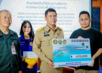 Gabenor Narathiwat, Boonchuey Homyamyen menyampaikan pampasan kepada Muhammad Yusri Udin pada majlis di Sungai Golok, Thailand.- IHSAN POLIS
