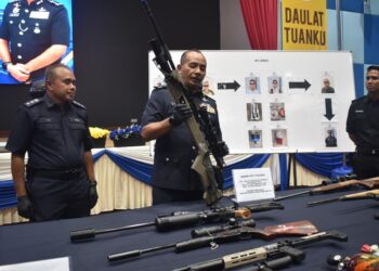 MUHAMMAD Abdul Halim (tengah) memeriksa senjata api yang dirampas dalam beberapa siri serbuan dalam sidang akhbar di IPK Perlis hari ini.-UTUSAN/ASYRAF MUHAMMAD