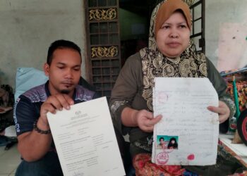 MUHD. Amirul Asyraf Abdul Aziz dan ibunya menunjukkan surat keputusan carian dari daftar daripada Jabatan Pendaftaran Negara untuk proses mendapat hak kerakyatan ketika ditemui di Kampung Apal, Besut, Terengganu semalam. -UTUSAN/WAN ZURATIKAH IFFAH WAN ZULKIFLI