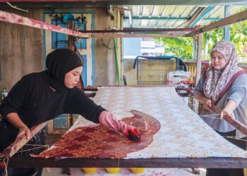 NUR Farhana Abd. Kadir (kiri) dan Nur Shakilah melakukan kerja-kerja mencanting dan mewarnakan batik yang dihasilkan mereka di Kampung Pasir Panjang, Kuala Terengganu, Terengganu. – MINGGUAN/PUQTRA HAIRRY