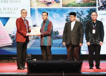 Dr. Mohd. Azman Yacob menerima buku 50 Tahun Jubli Emas daripada Dr. Cheong Soon Keng (kiri) selepas merasmikan Persidangan Saintifik Tahunan ke 21 di Kota Bharu. – UTUSAN/KAMARUL BISMI KAMARUZAMAN