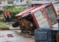 SEORANG wanita berjalan melewati sebuah kenderaan roda tiga yang terbalik akibat tiupan angin aufan Bavi di Wenling semalam. - AFP.