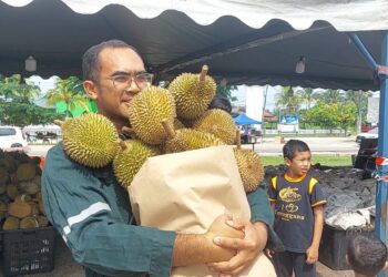 PELANGGAN membawa guni penuh dengan durian yang dibeli dengan harga RM100 di gerai di Kampung Balok di Kuantan, Pahang.