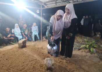 AHLI keluarga menyiram air mawar di pusara  Allahyarham Mohd. Aizat Husni di Tanah Perkuburan Islam Kampung Bukit Payong, Besut Terengganu. -  UTUSAN/WAN ZURATIKAH IFFAH WAN ZULKIFLI