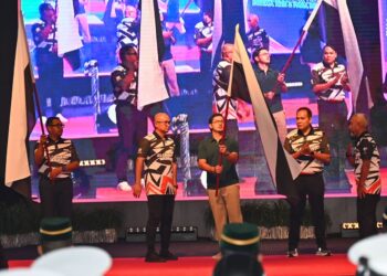 TENGKU Muhammad Iskandar Ri’ayatuddin Shah (tengah) mengibarkan bendera pada Majlis Penyerahan Bendera kepada Kontinjen Pahang ke Temasya Sukma dan Para Sukma Selangor sambil diperhatikan Fadzli Mohamad Kamal (dua dari kiri) di Dewan Jubli Perak Sultan Ahmad Shah di Kuantan, Pahang.