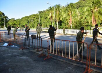 ANGGOTA tentera dan polis memeriksa kawasan jalan selepas satu alat letupan yang dipasang pada sebuah kereta diletupkan semalam. - AFP