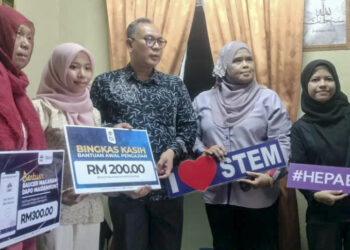 MOHD. Zamri Ibrahim (tengah) menyampaikan Bantuan Awal Pengajian dan Baucar Makanan kepada Nurul Amira Abdul Hamid (dua dari kiri) di Parit Jawa, Bagan Serai hari ini. – UTUSAN/WAT KAMAL ABAS
