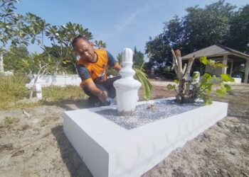 MUHAMAD Zuhri Mat Juhan mencuci dan mengecat semula belindan kubur di Tanah Perkuburan Islam Kampung Tembila, Besut, Terengganu. – UTUSAN/WAN ZURATIKAH IFFAH WAN ZULKIFLI