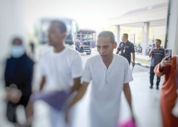 AMRAN Salleh (kanan) semasa dibawa polis untuk prosiding perbicaraan di Mahkamah Tinggi Kota Bharu, Kelantan. – UTUSAN/KAMARUL BISMI KAMARUZAMAN