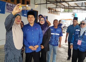 AHMAD bergambar bersama salah seorang penyokong ketika berkempen di Felda Air Tawar.