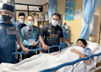 RAHMAD Mariman (kanan) melawat salah seorang pelajar yang mengalami kecederaan di Hospital Melaka hari ini. - UTUSAN/AMRAN MULUP