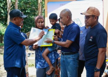 BARRUL Hisham Alias menyerahkan sijil kelahiran kepada lapan anak Zapni Abd. Wahab, 53, menerusi Program Menyemai Kasih Rakyat (MEKAR) di Kampung Johal, Kuala Krai, Kelantan hari ini-UTUSAN/KAMARUL BISMI KAMARUZAMAN.