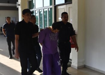 TERTUDUH (tengah) diiringi polis semasa menghadiri prosiding perbicaraan di Mahkamah Seksyen Pasir Mas, Kelantan. - UTUSAN/ROSMIZAN RESDI