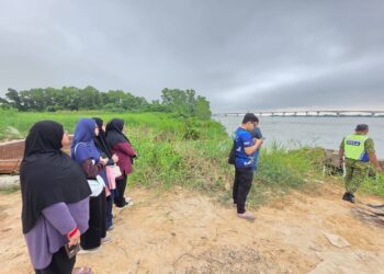 AHLI keluarga mangsa yang dipercayai terjatuh dari Jambatan Sultan Nazrin Shah di lokasi kejadian di Bagan Datuk. - UTUSAN/AIN SAFRE BIDIN