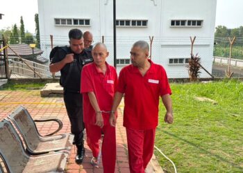 KHAIRUL Helmy Abd. Karim (kanan) dan Mohamad Irwan Abdul Halim dikawal warden penjara setelah mengaku bersalah terhadap dua pertuduhan mengugut di Mahkamah Majistret Sungai Petani, hari ini.