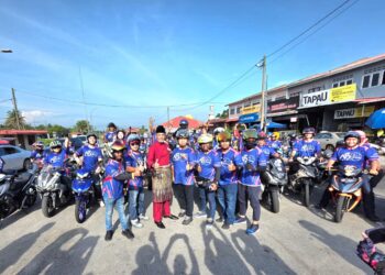 KHAIRY Jamaluddin (tengah) melancarkan baju Mat Motor Sungai Manik Team Haji Nazari Sabran di Dataran  Chenderong Balai di Pasir Salak hari ini. - UTUSAN/AIN SAFRE BIDIN