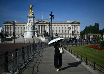 SEORANG individu menggunakan payung bagi melindungi diri daripada bahang panas berhampiran Istana Buckingham di London. - AFP.