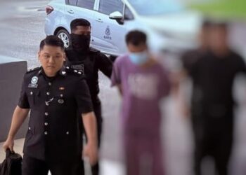 TERTUDUH (tengah) semasa dibawa polis semasa prosiding perbicaraan di Mahkamah Pasir Mas, Kelantan.