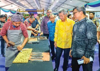 Shaharuddin Abu Sohot (dua dari kanan) melihat demonstrasi ukiran kayu selepas merasmikan Program Jelajah Mesra Festival Kraf Perak 2026 di Dataran Menara Condong, Teluk Intan, kelmarin.