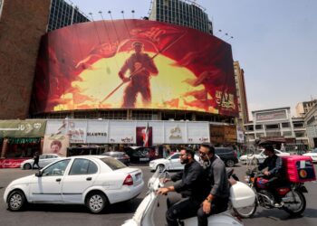 PEMANDU kenderaan melalui sebuah papan iklan politik di Dataran Valiasr, tengah Teheran. - AFP
