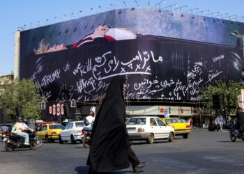 SEORANG wanita melintasi Dataran Enghelab di Teheran, berhampiran papan iklan gergasi anti-Amerika Syarikat (AS) yang memaparkan Presiden Donald Trump di dalam keranda dengan tulisan 'Kami bunuh Trump'.- AFP
