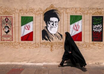 SEORANG wanita berjalan melalui mural bekas pemimpin tertinggi Iran, Ali Khamenei, di Dataran Valiasr di tengah Teheran.- AFP