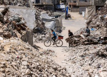 SEORANG kanak-kanak lelaki berbasikal melintasi runtuhan bangunan yang musnah di Khan Younis, selatan Gaza.- AFP