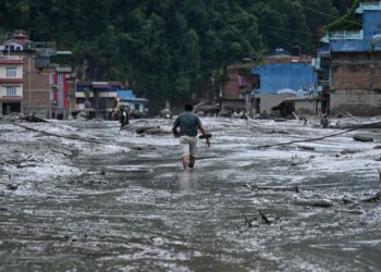 SEORANG penduduk meredah jalan yang diliputi lumpur tebal selepas banjir kilat dan bencana tanah runtuh melanda daerah Nuwakot, Nepal, Rabu lalu.- AFP