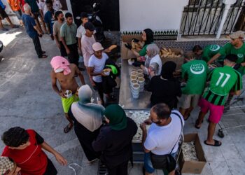 MIGRAN beratur untuk mendapatkan makanan yang diagihkan kumpulan bantuan Luna Blanca di wilayah Sepanyol di Afrika Utara, Ceuta.-AFP 