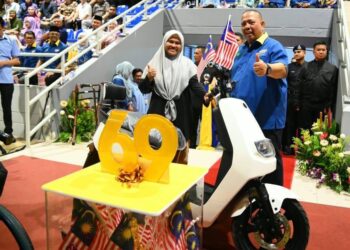 ABU Bakar Hamzah (kanan) menyerahkan motosikal elektrik kepada pemenang cabutan bertuah tempat pertama bersempena sambutan Hari Kebangsaan Ke-69  peringkat negeri ini di Kompleks Tuanku Syed Putra, Kangar, Perlis malam tadi.-UTUSAN