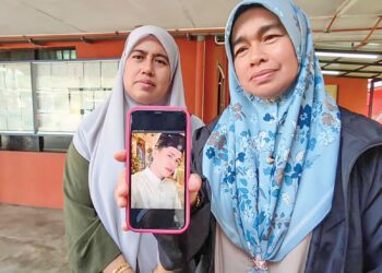 ROHANA Mukhtar (kanan) menunjukkan gambar adiknya, Muhamad Amin yang maut dalam kemalangan di Kilometer 80 Jalan Johor 
Bahru-Mersing, Kota Tinggi semalam.