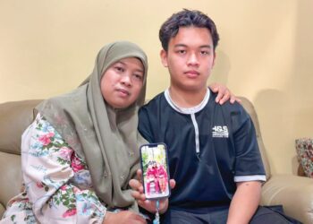 NORASMANI Ahmad bersama anak tunggalnya, Muhammad Harith Mirza menunjukkan gambar kenangan bersama arwah Mohd. Khairil ketika ditemui di Alor Setar, Kedah semalam.