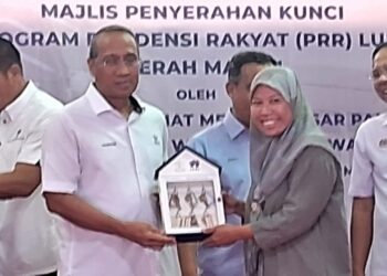 MOHAMMAD Fakhruddin Mohd. Ariff (dua dari kiri) menyerahkan kunci rumah Program Residensi Rakyat (PPR) Luit kepada penerima di perkarangan PRR Luit di Maran, Pahang. - FOTO/SALEHUDIN MAT RASAD