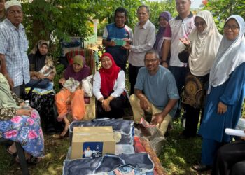 RAZAK Daud (belakang, lima dari kanan) menyampaikan sumbangan kepada ahli keluarga Selamah@Esah Hassan di Felda Jengka 12 di Jerantut, Pahang.
