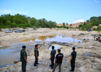 AHMAD Radzi Hussain (dua dari kiri) menunjukkan kawasan perlombongan dalam satu serbuan Op Gali Mega Zon Timur di Bukit Kor, Marang, Terengganu. - UTUSAN/PUQTRA HAIRRY