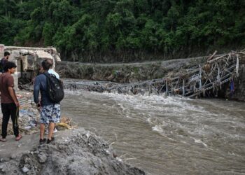 ORANG ramai berdiri berhampiran jambatan yang runtuh selepas banjir kilat melanda Devighat di daerah Nuwakot, Nepal.. - AFP