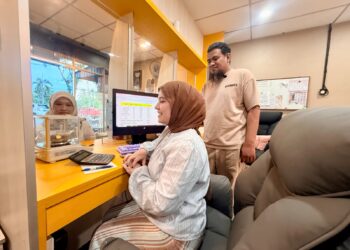 MOHAMAD Fakhmi Sabry (kanan) melihat kakitangannya memberi perkhidmatan kepada pelanggan yang menjual emas di Kedai Emas Fahmi di Taman Sena Indah, Kangar, Perlis semalam. – UTUSAN/ASYRAF MUHAMMAD
