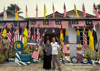 MOHD. Jumaro Marzuki bersama isterinya, Azizah Yakimi di hadapan kediaman mereka yang dipenuhi Jalur Gemilang ketika ditemui di Felda Raja Alias 4, Bandar 
Sri Jempol, Jempol, Negeri Sembilan. – UTUSAN/NOR SHAFIQAH MOHD. GHAZALI