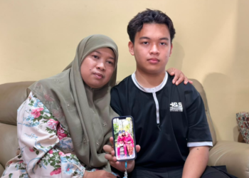 NORASMANI Ahmad disamping anak tunggalnya, Muhammad Harith Mirza menunjukkan gambar kenangan bersama arwah Mohd. Khairil ketika ditemui di Alor Setar, Kedah hari ini.
