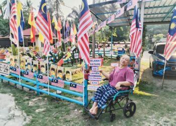 BIDIN Ariffin kelihatan bersemangat dan ceria ketika duduk berdekatan bendera Malaysia dan gambar tokoh negarawan di Felda Sungai Tekam di Jerantut, Pahang.