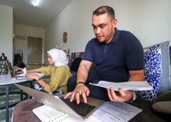 MUHAMMAD Faiz Norzani (kanan) dan isterinya, Nur’ain Nadhirah Mohd. Junaidi bekerja dari rumah berikutan pelaksanaan Dasar Hari Bekerja Hibrid (HBH) bermula 1 Ogos. – UTUSAN/FAISOL MUSTAFA