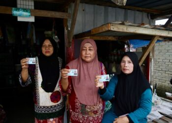PENDUDUK (dari kiri), Roziah Din, Fatimah Din dan Mariam Ahmad menunjukkan MyKad milik mereka di Kampung Tanjung Lembung, Bukit Malut di Pulau Langkawi, semalam. - UTUSAN/ SHAHIR NOORDIN