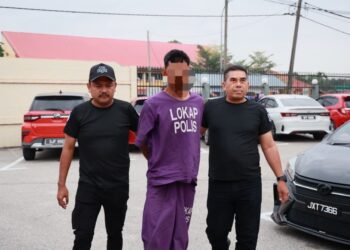 TERDUDUH diiringi dua anggota polis semasa prosiding perbicaraan di Mahkamah Majistret Machang, Kelantan hari ini.-UTUSAN/KAMARUL BISMI KAMARUZAMAN.