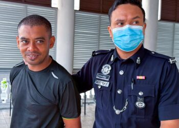 MOHD. Salim Kapoor Rahim (kiri) hanya tersenyum ketika diiringi anggota polis di Mahkamah Sesyen George Town, Pulau Pinang hari ini atas pertuduhan merompak serta mencederakan seorang lelaki warga India, 8 Ogos lalu.-UTUSAN/DANIAL SAAD