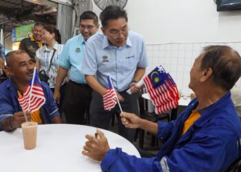 SIM Tze Tzin (dua dari kanan) ketika mengagihkan Jalur Gemilang kepada orang ramai termasuk penjaja serta peniaga di premis makanan di Sungai Nibong, George Town, Pulau Pinang.-UTUSAN/DANIAL SAAD