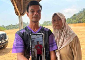 MOHD. Yusmiza Mamat (kiri) menunjukkan gambar anaknya yang belum ditemukan selepas dipercayai lemas di Sungai Kelantan berhampiran Kampung Batu Lada, Aur Duri, Kuala Krai, Kelantan sejak Selasa lalu. - UTUSAN/ROSLIZA MOHAMED