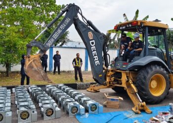 DENNIS Lim Kwang Keng (kanan) ketika melakukan gimik menggunakan jengkaut pada majlis pelupusan pelbagai barangan kes bernilai RM13.6 juta di Stor Barang Kes Pusat, Kepala Batas, Pulau Pinang.-UTUSAN/ISWAN SHAFIQ ISA