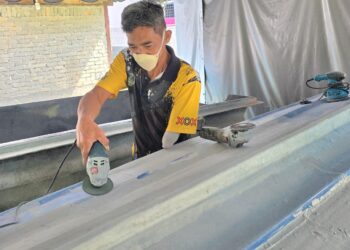 HERRY Nizam Salleh melakukan kerja akhir pada bot yang ditempah oleh pelanggan di bengkelnya 
di Kampung Bahagia di Teluk Intan, Perak. – UTUSAN/AIN SAFRE BIDIN